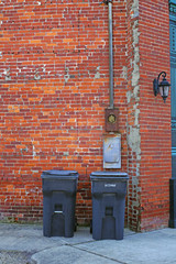Two trash cans against a brick wall