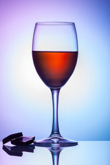 On the table is a glass of wine on a colored background