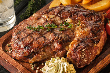 Ribeye steak with potatoes, onions and baked cherry tomatoes. Juicy steak with flavored butter