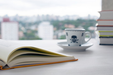Open book and coffee cup in front of a window