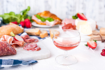 Appetizers table with italian antipasti snacks and wine in glasses. Salami and bruschetta with fresh vegetables on a white background. Free space for text. Traditional snacks for wine.