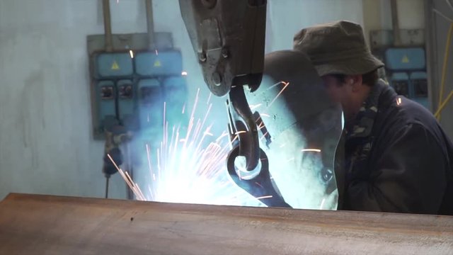 Welder working steel with his soldering iron tool machine with a lot of sparks. The blacksmith or locksmith industry it&rsquo;s a very hard job for a man.
