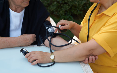 Doctor checking old woman patient arterial blood pressure, close-up