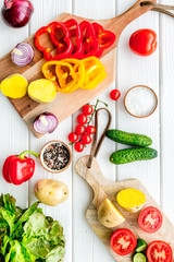 cooking with raw vegetables on white wooden background top view