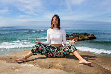 woman doing yoga by the ocean