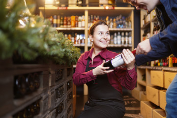Photo of woman seller with bottle of wine and buyer