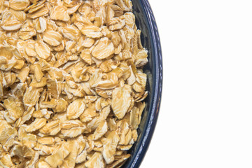 Raw oat cereal in a blue bowl over white background