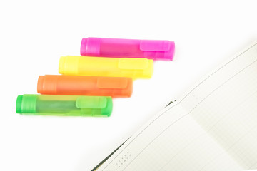 isolated yellow, orange, green and purple markers on the daily planner on the white background