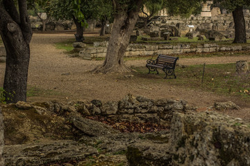 stone ruins of the ancient Greece city in park outdoor natural environment road for walking with wooden bench touristic heritage place
