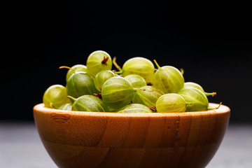 Photo of gooseberry berries in wooden cup.