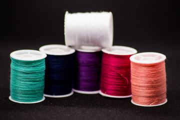 Colourful thread spools on a black background