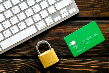 Data protection concept with locker and credit card on keyboard wooden background top view