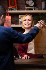Picture of smiling seller blonde giving paper bag to man