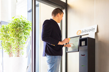 Bitcoin ATM machine being used by businessman for buying cryptocurrency and other altcoins