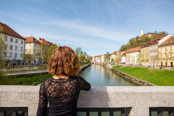 Fototapeta na wymiar Young woman is admiring old buildings, apartments and castle in old part of Ljubljana, Slovenia