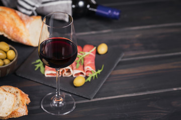Glass of red wine with slices of cured ham or Spanish jamon serrano or Italian prosciutto crudo,...