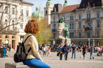 Young woman is sitting in the Presern square and admiring Presern monument in Ljubljana, Slovenia