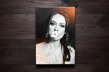 Photography printed on canvas. Portrait of a beautiful young woman. Photo hanging on brown wooden wall
