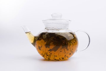 Herbal tea in a teapot with fresh herbs isolated on white background