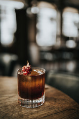 A close up shot of classic Old Fashioned cocktail served with a cube of ice and garnished with cranberries. Concept of bourbon whisky, spirits and alcohol.