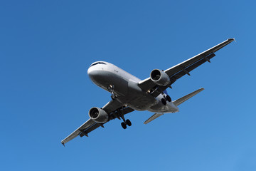 Fototapeta na wymiar Zweistrahliges Flugzeug in der Luft vor der Landung und blauer Himmel - Stockfoto