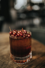 A close up shot of classic Old Fashioned cocktail served with a cube of ice and garnished with cranberries. Concept of bourbon whisky, spirits and alcohol.
