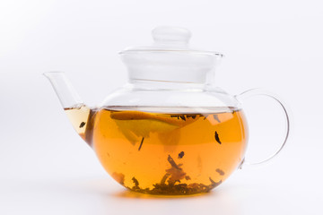 Glass teapot with black tea nad fresh orange isolated on white background