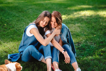 Fototapeta premium Two friends are sitting on the green lawn in the park.