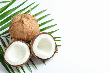 Fototapeta na wymiar Two coconut one of which split with palm branch on white background