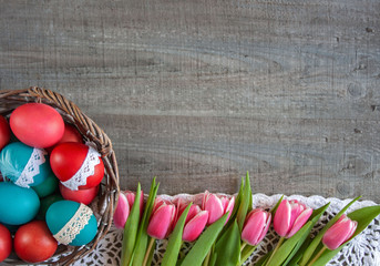 Wielkanocne tło - kosz z kolorowymi pisankami i różowe tuliapny - obrazy, fototapety, plakaty