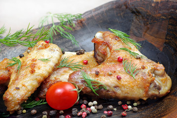 Chicken baked wings on wooden background. chicken wings, tomatoes and pepper mix, close-up