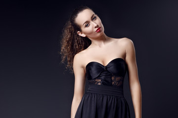 Portrait of fashionable elegant girl in black evening dress on dark background. Evening look. Concept formal prom party