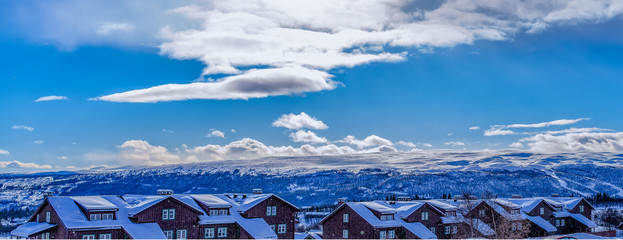 Wooden houses in Beitostolen, some snow in the air and Jotunheimen in the background