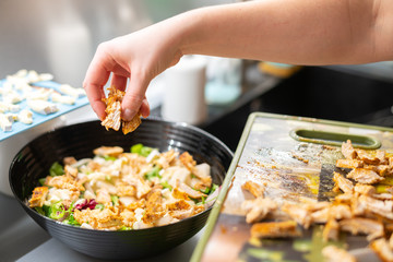 Woman prepares a salad with chicken.