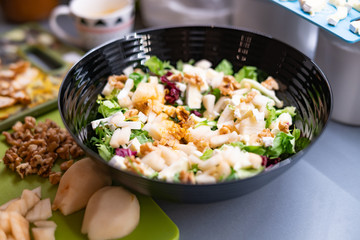 Woman prepares a salad with chicken.