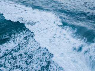 Aerial view of wave breaking into white foam.