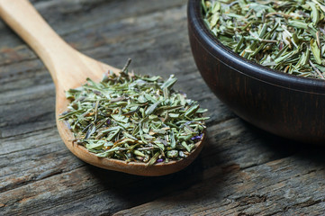 Heap of dry thyme in wooden spoon and in bowl on wooden background. Dried spice zahter thyme and...