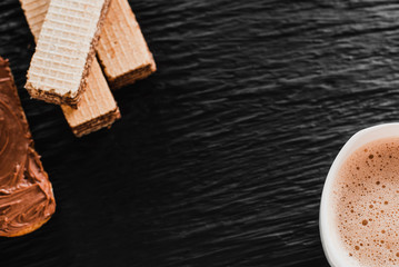 Close-up of coffee cup with roasted coffee beans on wooden background. View from top