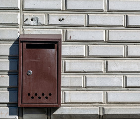 old mail box hanging on the white brick wall