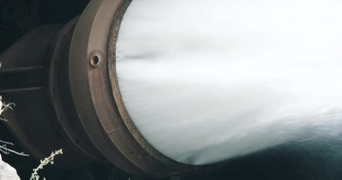 Rushing water coming out of dam spillway drainage pipe
