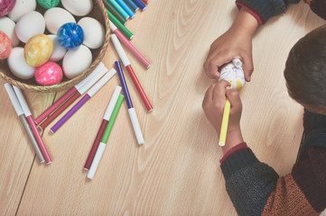 children painting easter eggs with their mom's help and with markers at home