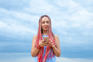 Caucasian woman with african pigtails using smartphone outdoors