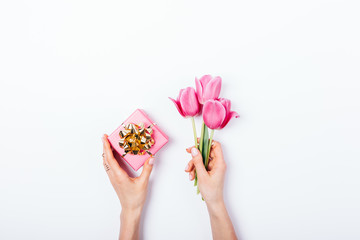 Woman's hands holding small pink gift box with golden bow