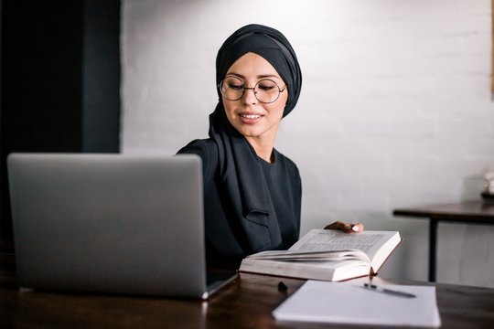 Arab women in hijab working at laptop in cafe