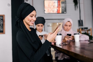 Muslim woman in hijab communicates via video sitting in a cafe