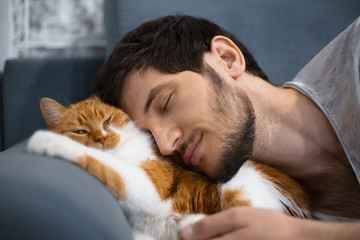 Sleeping young man and red white cat.