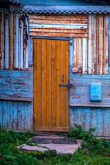 Grunge style background image, old wooden brown door on a contrasting blue shabby wall