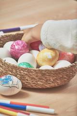 children painting easter eggs with their mom's help and with markers at home