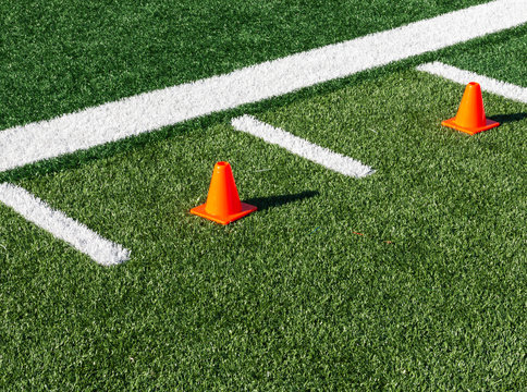 Two orange cones between hash marks on football field