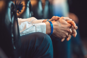 close-up of the clasped male hands sitting on a leather chair. the speaker is waiting for his turn at the business conference